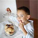 A little boy taking some cookies in a jar