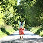 s A 5 years old girl wearing butterfly wings, in the countryside