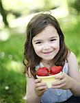 A 5 years old girl eating  strawberries in the countryside