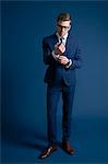 man in blue suit, glasses, blue background, watch, cufflinks; tie