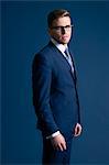 man in blue suit, glasses, blue background, tie