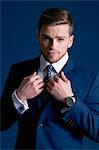 man in blue suit, tie, beard; cufflinks; blue background, watch