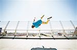 Young man somersaulting on a bridge.