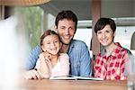 Family sitting together at table with open book, portrait