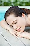 Young woman lying down, sunbathing with eyes closed, cropped