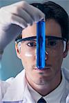 Chemist scrutinizing test tube containing blue liquid