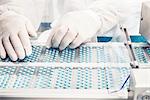 Worker inspecting pills on blisterpack conveyer belt