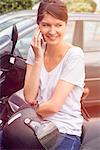 Woman sitting on parked motorcyle, talking on cell phone