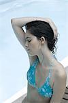 Young woman in bikini holding up wet hair