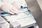 Worker placing pills in tablet trays moving along conveyor belt