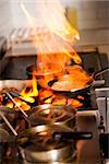 Chef cooking with flame in a frying pan on a kitchen stove