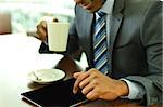 Businessman using digital tablet while having coffee at cafe