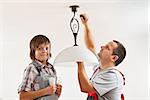 Changing an incandescent lightbulb with a fluorescent one - boy helping his father