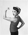 woman brunette in a blue shirt with a scarf on her head and hair in a retro style biceps show-off