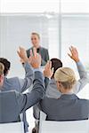 Business team raising hands during conference in meeting room