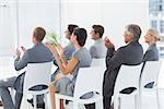 Smiling business team applauding during conference in meeting room