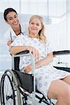 Doctor and patient in wheelchair smiling at camera in hospital