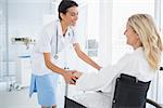 Happy doctor smiling at her patient in wheelchair in hospital