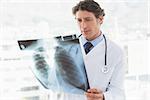 Serious doctor looking at X-ray in medical office