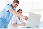 Doctors working with laptop computer in medical office