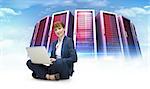 Businesswoman using laptop against composite image of server towers