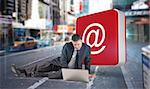 Mature businessman sitting using laptop against blurry new york street