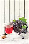 Glass of red wine and clusters fresh grape with leaves. Vintage toned photo.