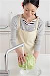 Woman washing cabbage in an open kitchen