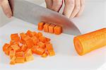 Close up of woman's hands slicing carrots with a kitchen knife