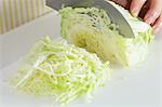 Close up of woman's hands cutting cabbage with a kitchen knife