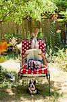 Woman with rollers in her hair reads in her garden with a Boston Terrier