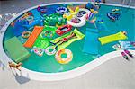 Boy wearing flippers floats in a pool full of inflatable toys