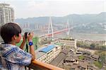 Boy photographing the Yangtze river cable car, Chongqing, China