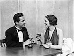 1930s 1940s COUPLE DRINKING TOASTING CLUB TABLE SMOKING CIGARETTE MAN WOMAN MEN WOMEN COUPLES TUXEDO MARTINI RESTAURANT PARTY