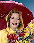 1960s SMILING WOMAN UNDER RED UMBRELLA YELLOW RAINCOAT HOLDING SPRING FLOWERS