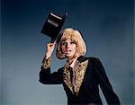 1960s BLOND WOMAN DANCER LOOKING AT CAMERA TIPPING BLACK TOP HAT COSTUME SEQUINED LAPELS AND CUFFS