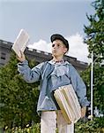 1960s BOY SELLING NEWSPAPERS WEARING BALL CAP BLUE JACKET