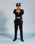 1970s FULL FIGURE STANDING AFRICAN AMERICAN MAN POLICEMAN OFFICER POINTING FIREARM AND LOOKING AT CAMERA