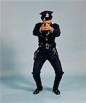 1970s FULL LENGTH MAN AFRICAN AMERICAN POLICE OFFICER IN ACTION STANCE AIMING REVOLVER AND LOOKING AT CAMERA