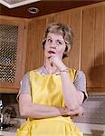 1960s THOUGHTFUL HOUSEWIFE WEARING YELLOW APRON