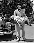 1950s DISTRAUGHT MAN LOOKING AT CAMERA CARRYING UNCONSCIOUS AND INJURED CHILD THAT WAS HIT BY A CAR