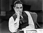 1930s 1940s MAN SEATED ELBOWS ON TABLE FACE LEANING ON HAND SERIOUS EXPRESSION WEARING SHIRT TIE VEST LOOKING AT CAMERA