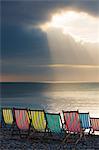 Empty deck chairs on a beach with a storm threatening.