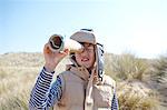 Young boy on beach, looking through pretend telescope