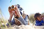 Two young boys on beach, looking through pretend binoculars