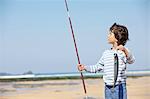 Young boy holding up fishing rod and fish