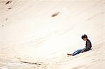 Young boy sitting on sandy hill