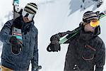 Two men carrying skis in snow