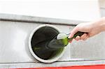 Person recycling wine bottle in bottle bank