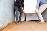 Two teenage boys recycling white goods in recycling depot